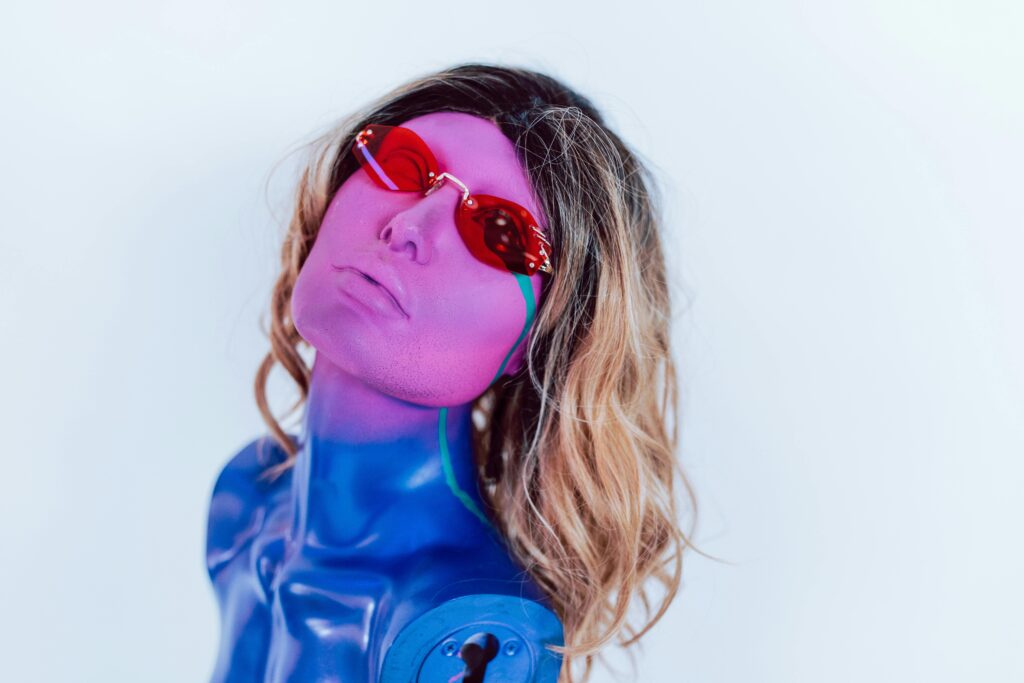 A colorful abstract mannequin wearing sunglasses against a light background.