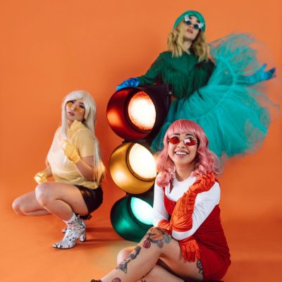 Three friends in colorful retro outfits enjoy a fun costume party.